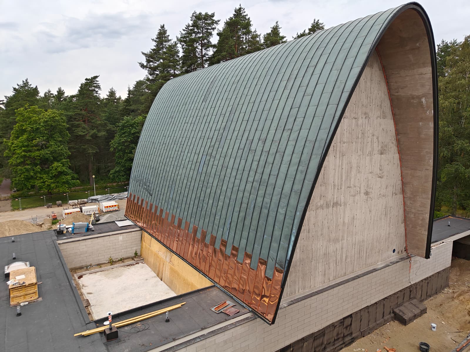 Kaareva ja erittäin jyrkkä kuparinen konesaumakatto, jonka alaosaa on uusittu.